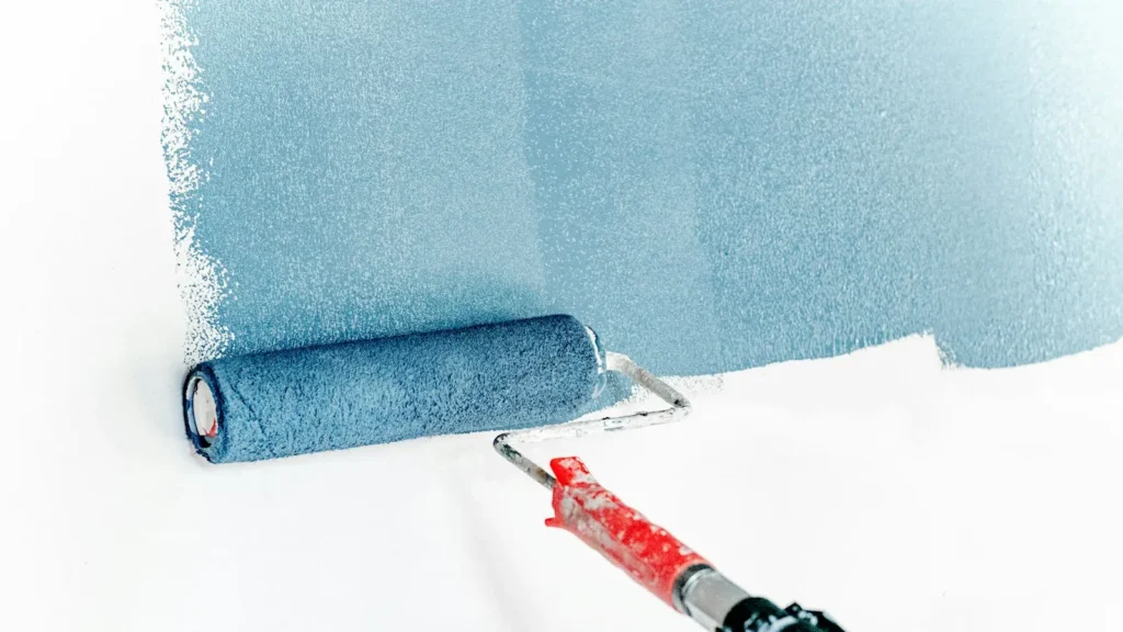Person rolling fresh paint on a living room wall, applying interior painting tips for a smooth finish