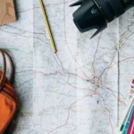 Traveler with a map, notebook and coins on a table, getting ready to plan a budget trip
