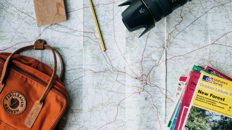 Traveler with a map, notebook and coins on a table, getting ready to plan a budget trip