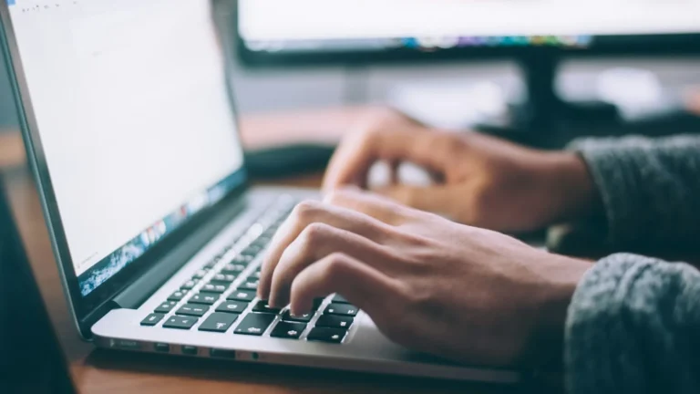 Person working at a desk trying to speed up a slow laptop by checking running apps and updates