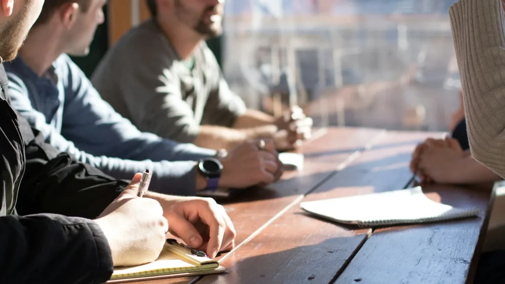 Entrepreneur writing a small business plan with charts and notes spread across a wooden desk