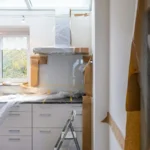 Homeowners reviewing blueprints and cabinet samples during kitchen remodel planning in a gutted kitchen