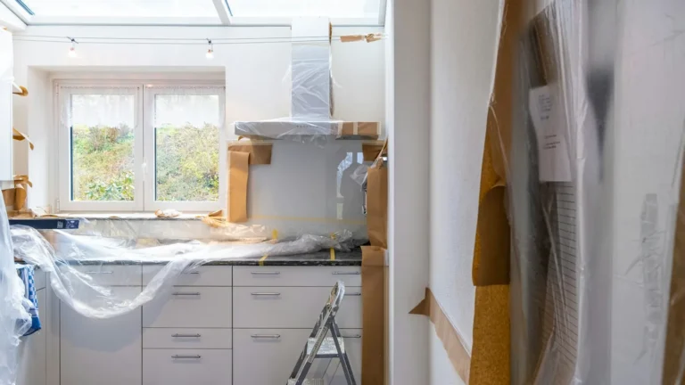 Homeowners reviewing blueprints and cabinet samples during kitchen remodel planning in a gutted kitchen